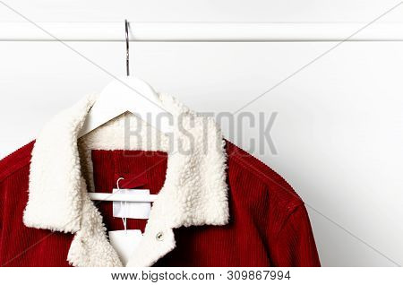 Red Corduroy Men's Jacket On White Coat Hanger On Rod Against Light Wall Flat Lay Copy Space. Male F