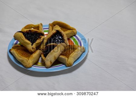 Hamantash Purim Blueberry And Apricot Jam Cookies On Colored Plate With White Sheet Background