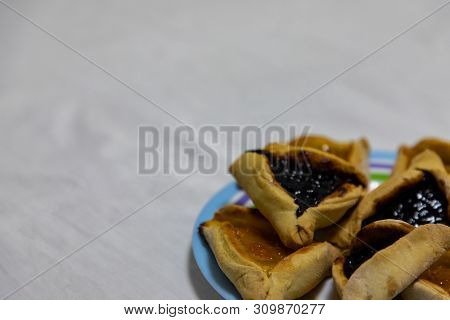 Hamantash Purim Blueberry And Apricot Jam Cookies On Colored Plate With White Sheet Background