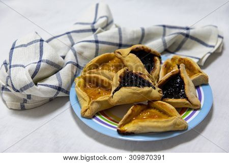 Hamantash Purim Blueberry And Apricot Jam Cookies On Colored Plate With A Plaid Blue Rag And A White