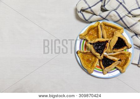 Hamantash Purim Blueberry And Apricot Jam Cookies On Colored Plate With A Plaid Blue Rag And A White