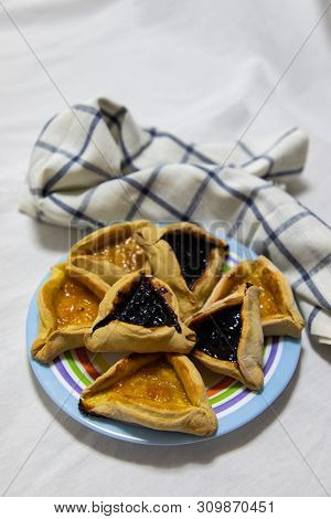 Hamantash Purim Blueberry And Apricot Jam Cookies On Colored Plate With A Plaid Blue Rag And A White