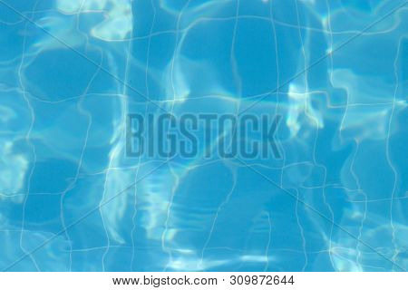 Water Vibrations In The Swimming Pool With Sun Reflection. Blue Swimming Pool Surface, Water Backgro