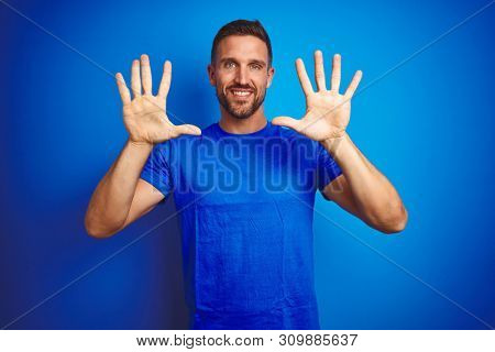 Young handsome man wearing casual t-shirt over blue isolated background showing and pointing up with fingers number ten while smiling confident and happy.