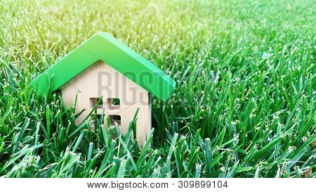 Miniature Wooden House On Grass. Real Estate Concept. Eco-friendly And Energy Efficient House. Buyin