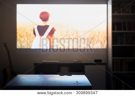 Home Cinema: Watching A Film From A Video Projector In A Room. Dim Living Room With A Cinematic Pict