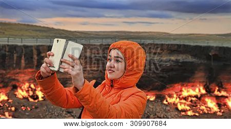 Turkmenistan, Darvaza - March 21, 2019:   Girl Makes Selfie On The Background Of The Burning Crater 