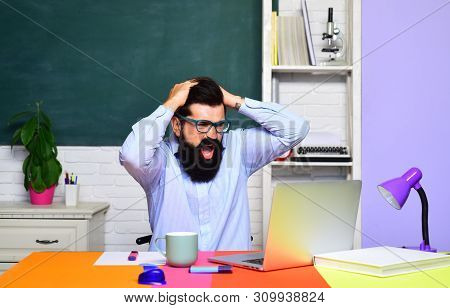 Angry Male University Student Near Chalkboard In Classroom. Teacher Preparing For University Exam. E