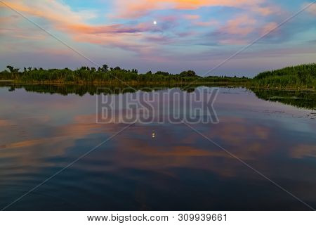 Scenic Summer Sunset Over The Lake. Pink Clouds Are Reflected In The Water Surface. Ukraine. Near Vi