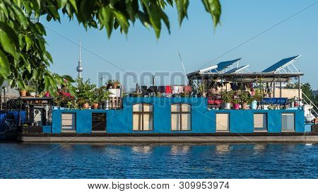 Blue Houseboat Rests In Treptow In The River Spree. Berlin. Germany
