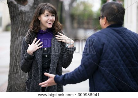 Female Pedestrian Walking Into A Friend By Coincidence On The Street.  They Are Meeting And Greeting