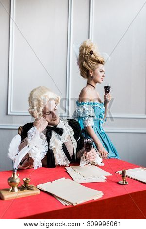 Sad Victorian Man In Wig Holding Glass Wine Near Pompous Woman