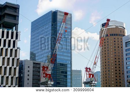 Closeup Hoisting Cranes Working On City Landscape View And Glass Office Building With Blue Sky And S