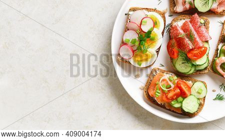 Close Up View Of Open Sandwiches With Meat, Vegetables, Seafood On Plare Over Light Stone Background