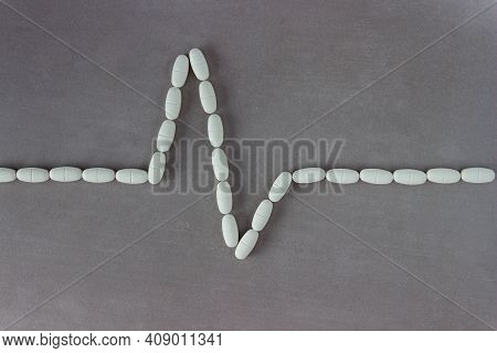 Pills Laid Out On A Gray Background In The Form Of A Heart Rate. Pulse, Heartbeat. The Concept Of He