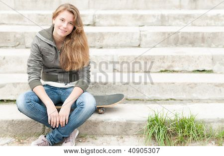 PortrÃ¤t von hÃ¼bschen MÃ¤dchen mit Skateboard im Freien.