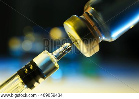Filling Syringe With Vaccine From Vial On Blurred Background, Closeup