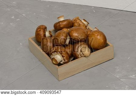 Royal Brown Champignons - Agaricus Bisporus. Fresh Mushrooms In Wooden Box On Concrete Gray Backgrou