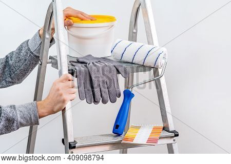 The Plaster Painter Is Ready To Paint The Wall. In The Hands Of A Roller And Brush. A Stepladder And