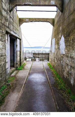 Abandoned Ruins Of An Old Costal Artillery Emplacement With Rail Road Tracks Leading To Viewer Throu