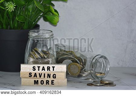 Text On Wood Block With Glass Jars Of Multicurrency Coins And Potted Plant - Start Saving More. Savi