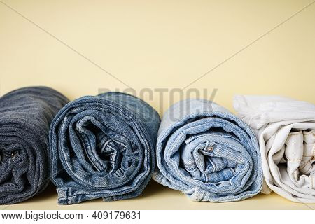 Folded Jeans In A Roll On A Yellow Background, Space For Text.