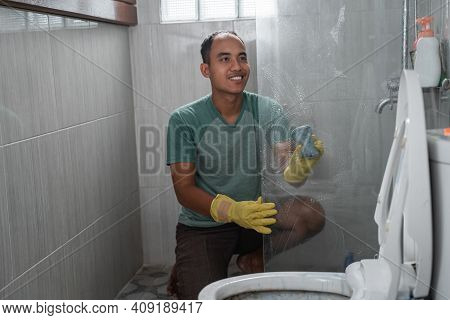 A Man Wearing Gloves Cleaned The Toilet Glass Divider