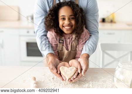Happy Loving Family. Smiling African American Little Girl And Her Father Holding Dough In Heart Shap