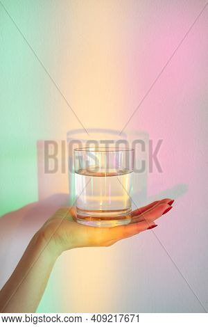 Clean Water. Rainbow Light. Liquid Nutrition. Healthy Life. Nature Magic. Female Hand Holding Glass 