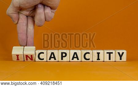 Capacity Or Incapacity Symbol. Businessman Turns Wooden Cubes And Changes The Word 'incapacity' To '
