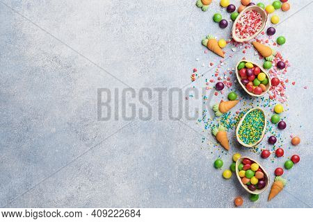 Chocolate Easter Eggs And Colorful Sweets On Gtay Background Greeting Card. Top View. Flat Lay With 