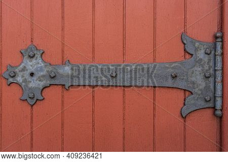Rustic Door Hinge On A Red Painted Door Of An Old Church
