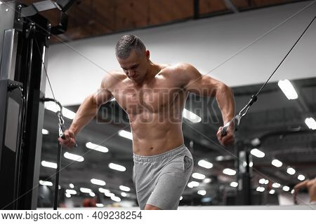 Muscular Athletic Bodybuilder Standing Training Chest And Shoulders Muscles On Fitness Equipment Wir