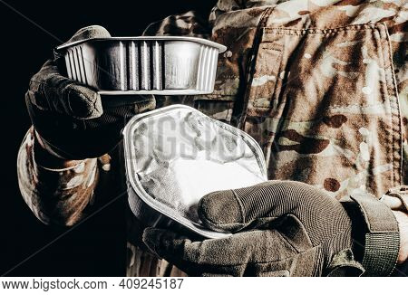 Photo Of Soldier In Camouflaged Uniform And Tactical Gloves Holding Canned Food Field Ration On Blac