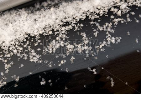 Snowflakes Lie On The Dark Surface Of The Car Visor
