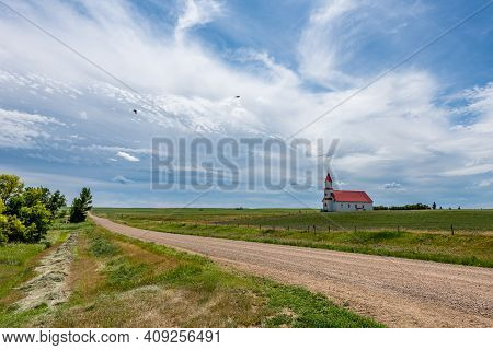 Birds Flying Over A Gravel Road In The Country Leading To The Historic St. Martin's Roman Catholic C