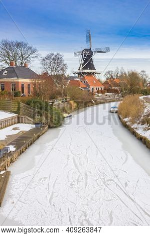 Historic Windmill At The Frozen River In Mensingeweer, Netherlands