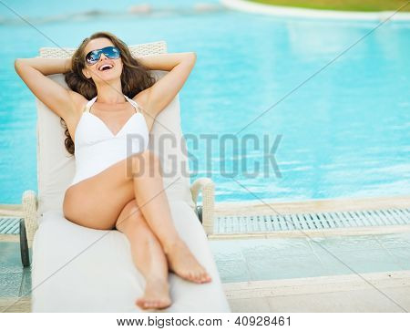 Šťastná mladá žena v plavkách na Chaise-longue bazénu