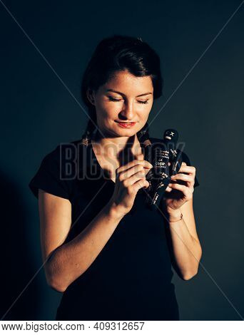 Smile Young Woman Holding A Black Voodoo Doll - Isolated On Black Background
