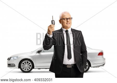 Professional ature man in a suit and tie holding a car key from a new silver car isolated on white background