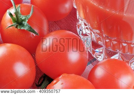 Half Full Glass With Tomato Juice With Pulp Stands On A Table Next To Tomatoes On A Branch Close-up 