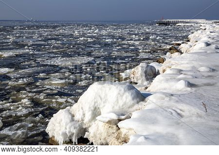 Icy Road To The Lighthouse On Mangalsala Pier In Baltic Sea Located At Riga Sea Port, Latvia, Europe