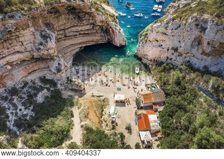 Aerial View Of Tourists Sunbath Swim At Stiniva Cove Beach Of Adriatic Sea On Vis Island In Croatia 