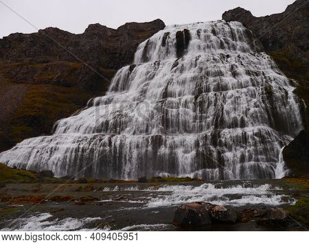A Waterfall With A Mountain In The Background
