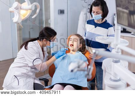 Dentist Using Mirror In The Course Of Kid Mouth Examination Sitting On Dental Chair. Dentistry Speci