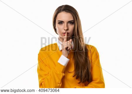 Portrait Of Young Brunette Woman Keeping Finger At Her Mouth, Saying Shh, Hush, Tsss. Silence And Se