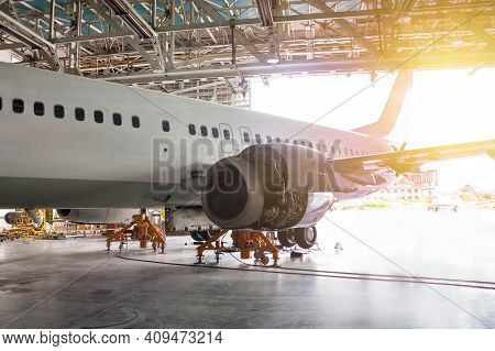 White Passenger Airliner Under Maintenance In The Hangar. Repair Of Jet Plane Engine On The Wing And