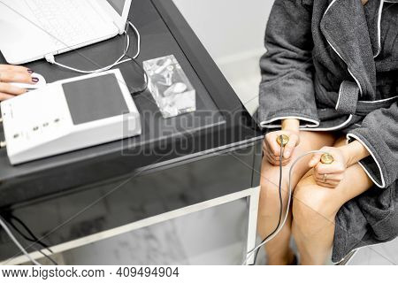 Woman Takes Hold Of The Brass Handpieces Of Bioenergetic Testing Device