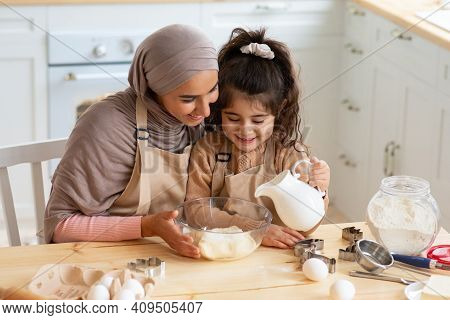 Young Muslim Mom Baking Together With Her Little Daughter In Kitchen. Cute Little Arab Girl Helping 