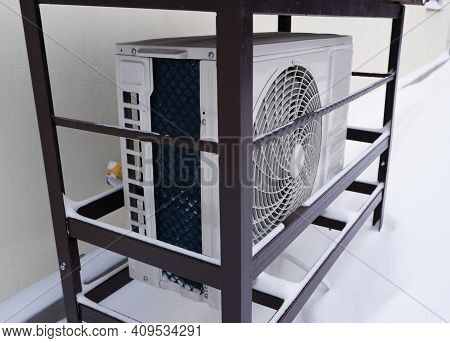 The Outdoor Unit Of The Air Conditioner (air-to-air Heat Pump) In The Snow During Winter Operation.